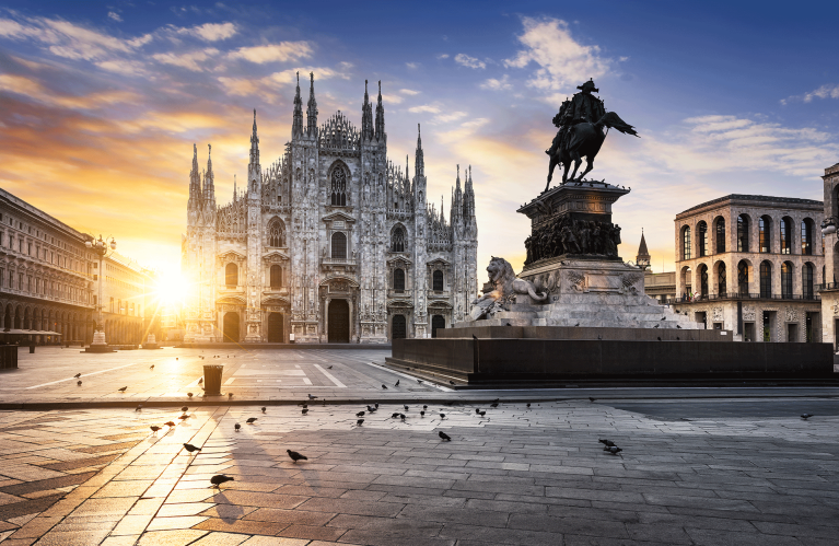 De zon komt op achter de Duomo van Milaan