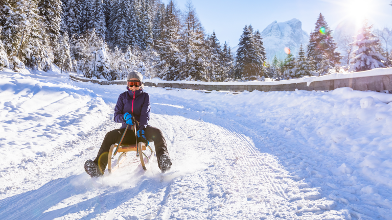winter-mountain-girl-tobogganing-sledding