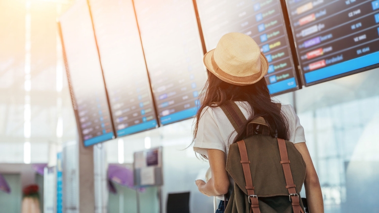 girl-at-airport-looking-at-departure-screens