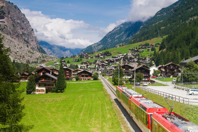 Glacier Express, der durch ein traditionelles Dorf in der Nähe von Zermatt fährt