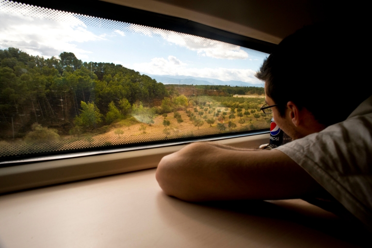Man looking at scenic landscape from AVE train window, Almeria-Granada, Spain